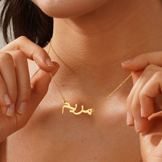 Gold necklace with Arabic script worn by a person