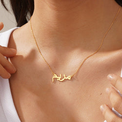 Gold necklace with Arabic script worn by a person
