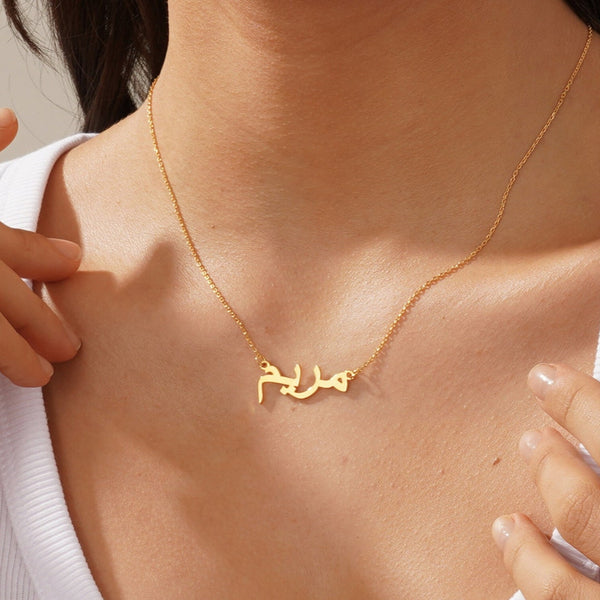 Gold necklace with Arabic script worn by a person
